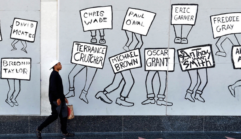 한 남성이 경찰의 과잉진압으로 사망한 흑인들의 이름을 그려넣은 벽화 앞을 지나가고 있다.[사진=뉴시스]