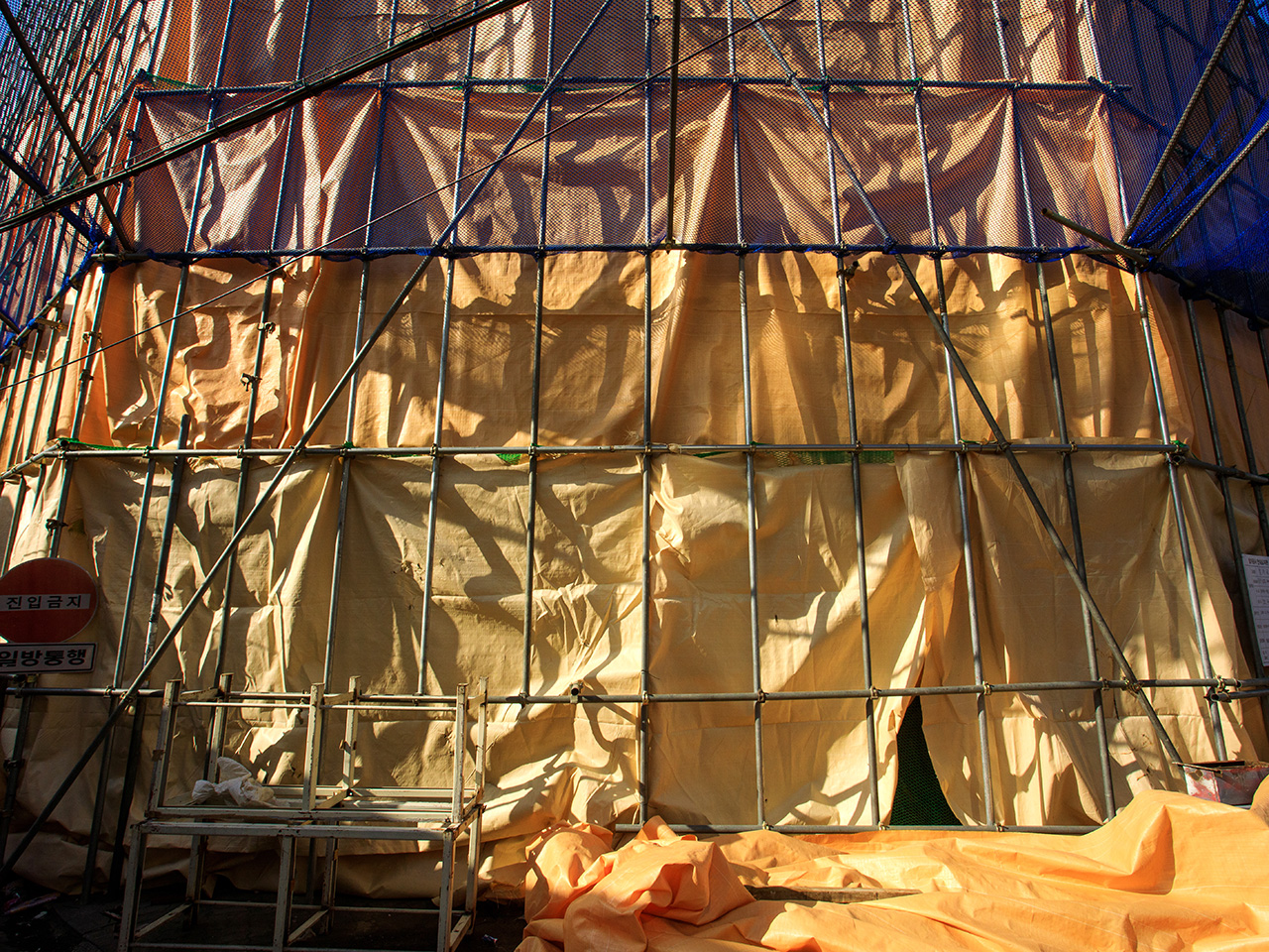 건물 해체를 앞두고 설치한 비계 뒤로 오후 햇살이 넘어간다. 해가 뜨고 지듯이 건물도 태어나고 사라진다. [사진 | 오상민 작가]